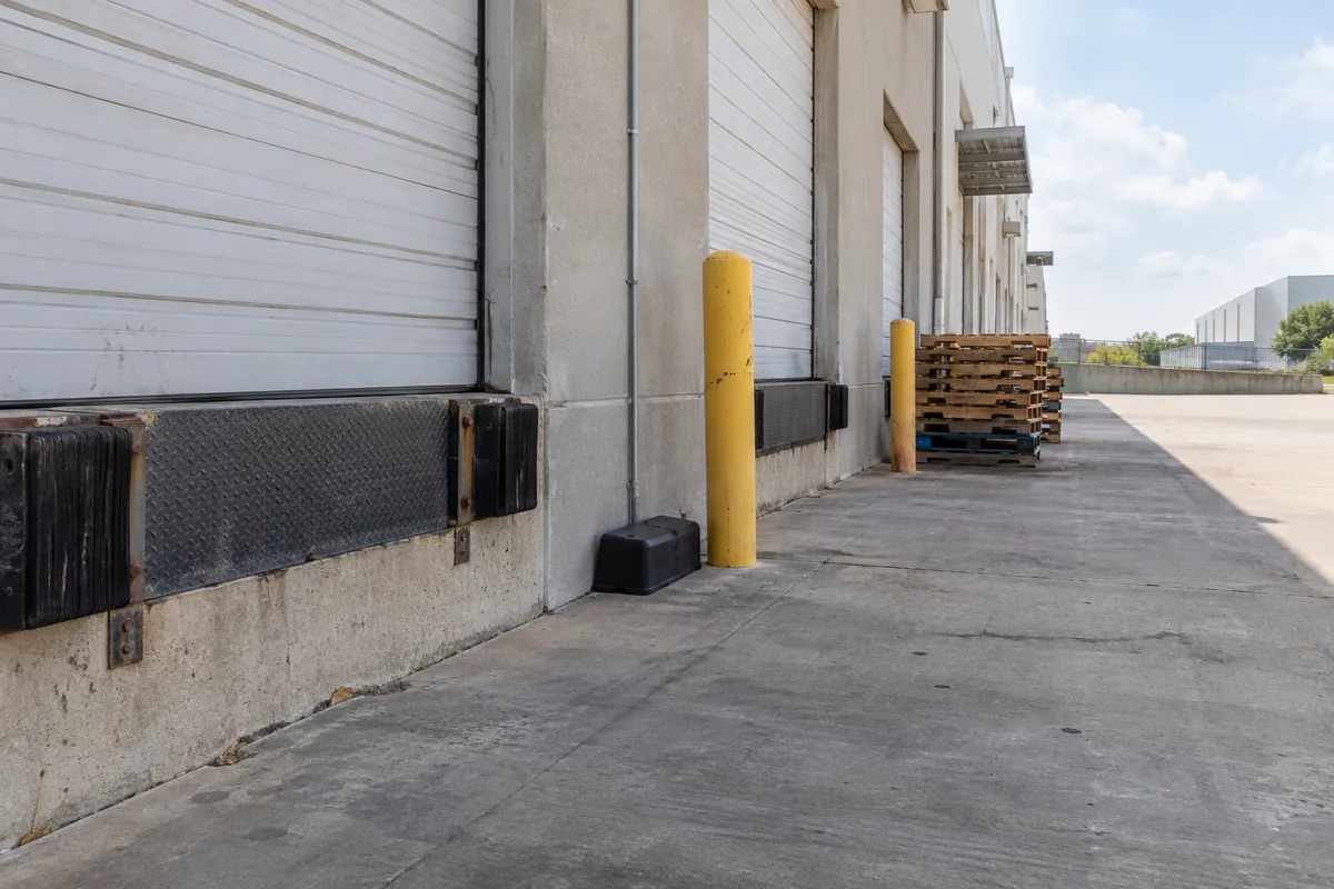 Loading dock doors at a commercial building with a bait station beside the wall, commercial mold remediation in Denver, CO